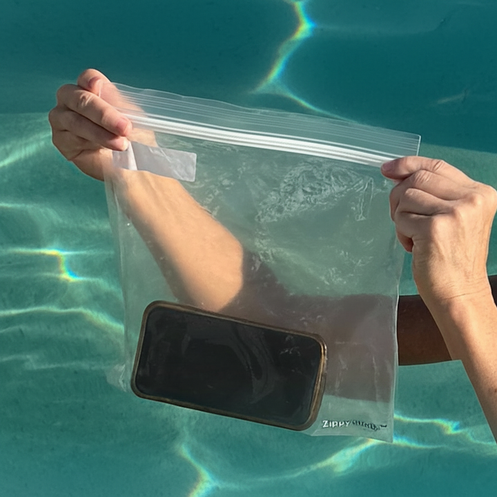 Person holding a clear plastic bag with a phone inside over the water